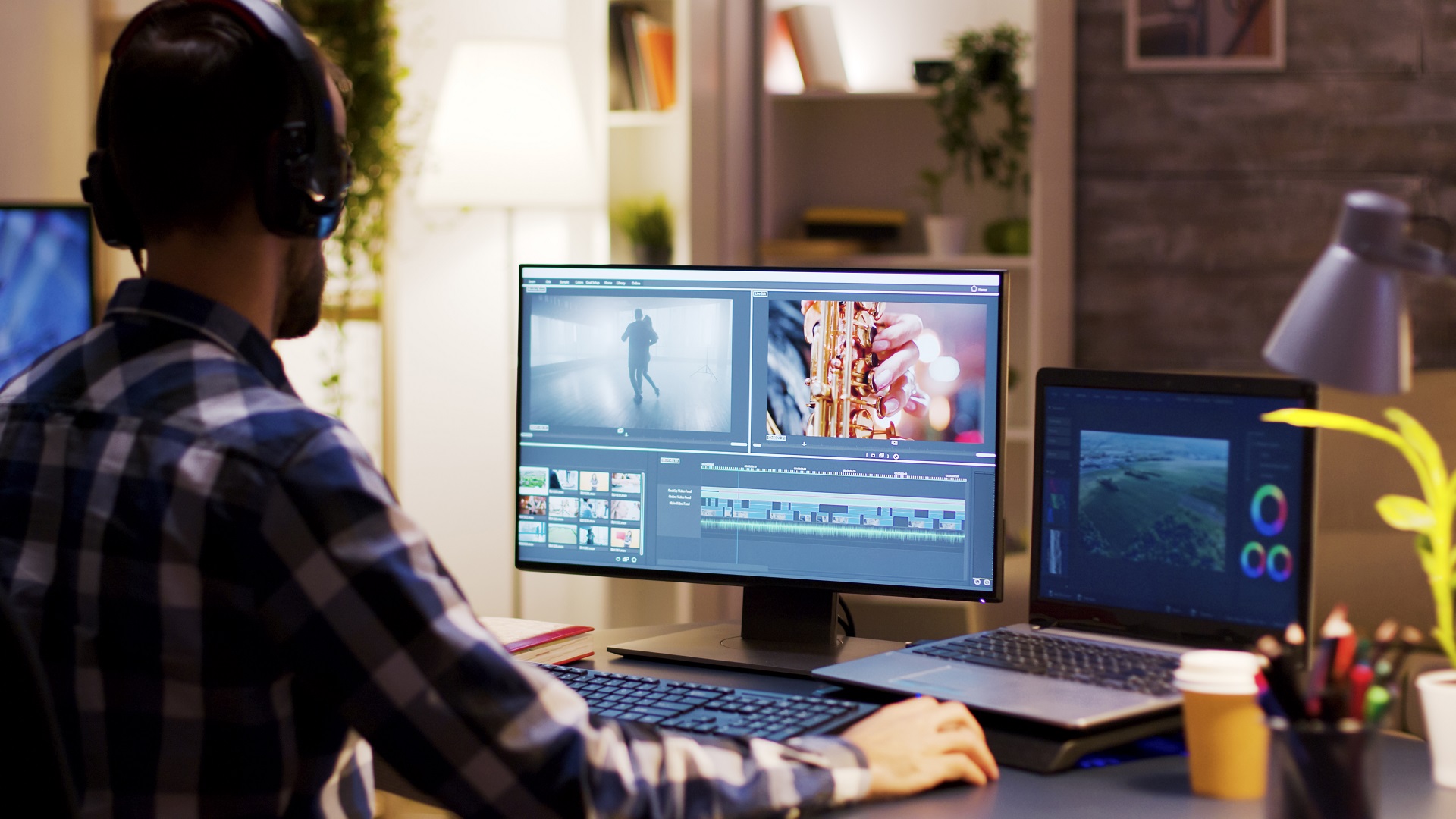 Film maker pointing at the monitor in home office while working on post production for a movie. Video editor wearing headphones.